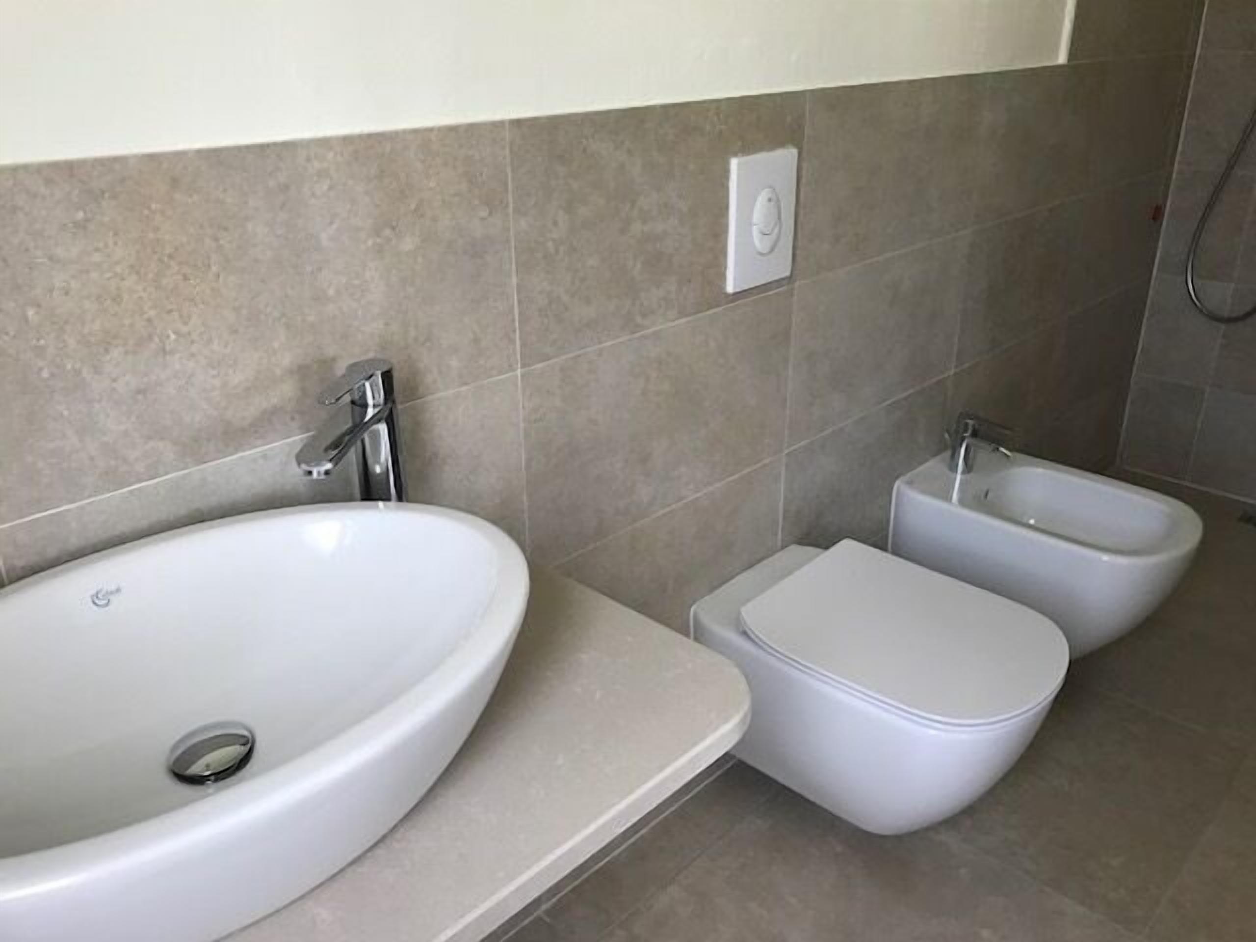 Une salle de bain avec un grand lavabo blanc, un bidet et des toilettes.