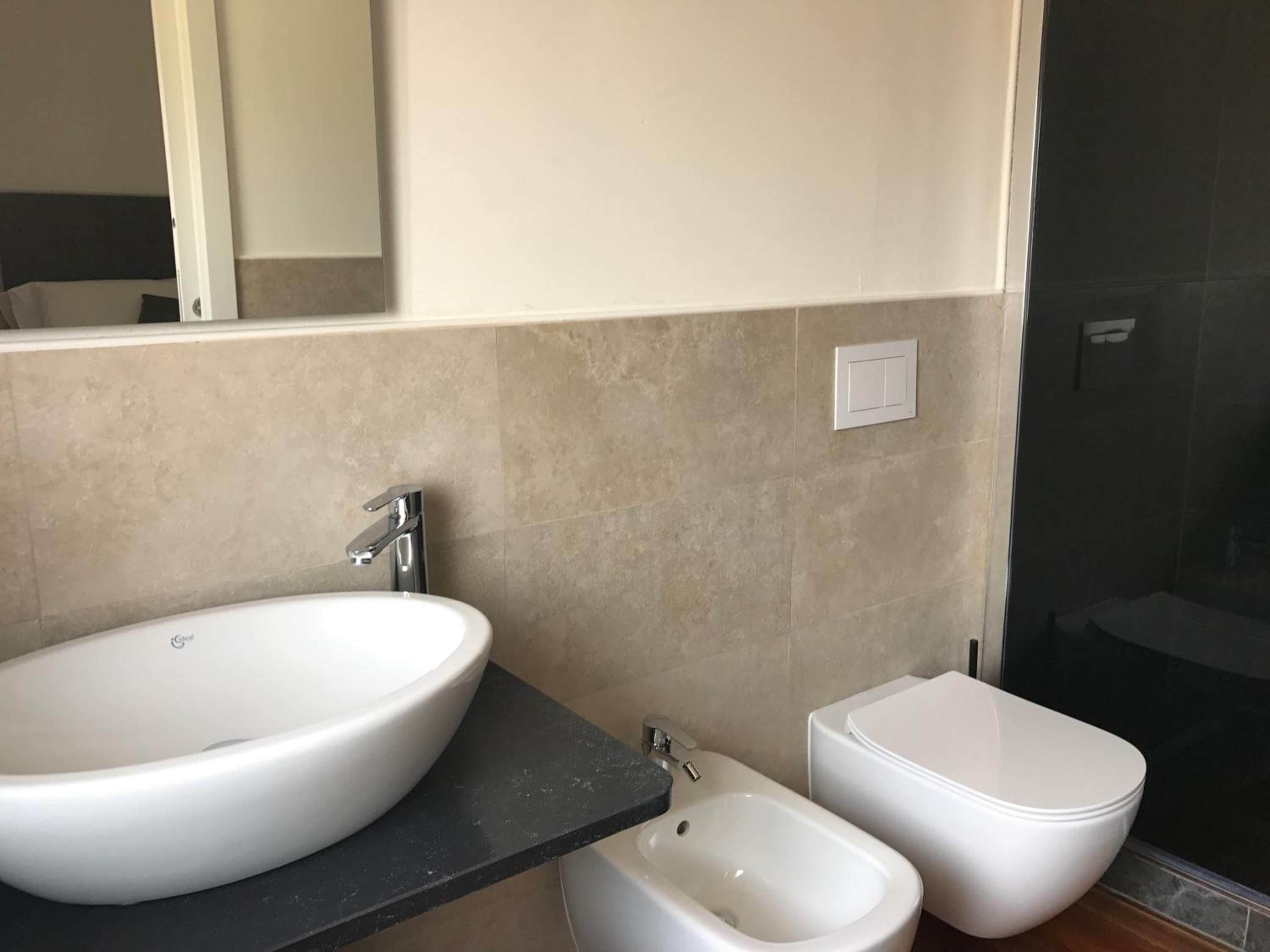 Un baño moderno con un lavamanos grande de color blanco, un bidé y un inodoro.