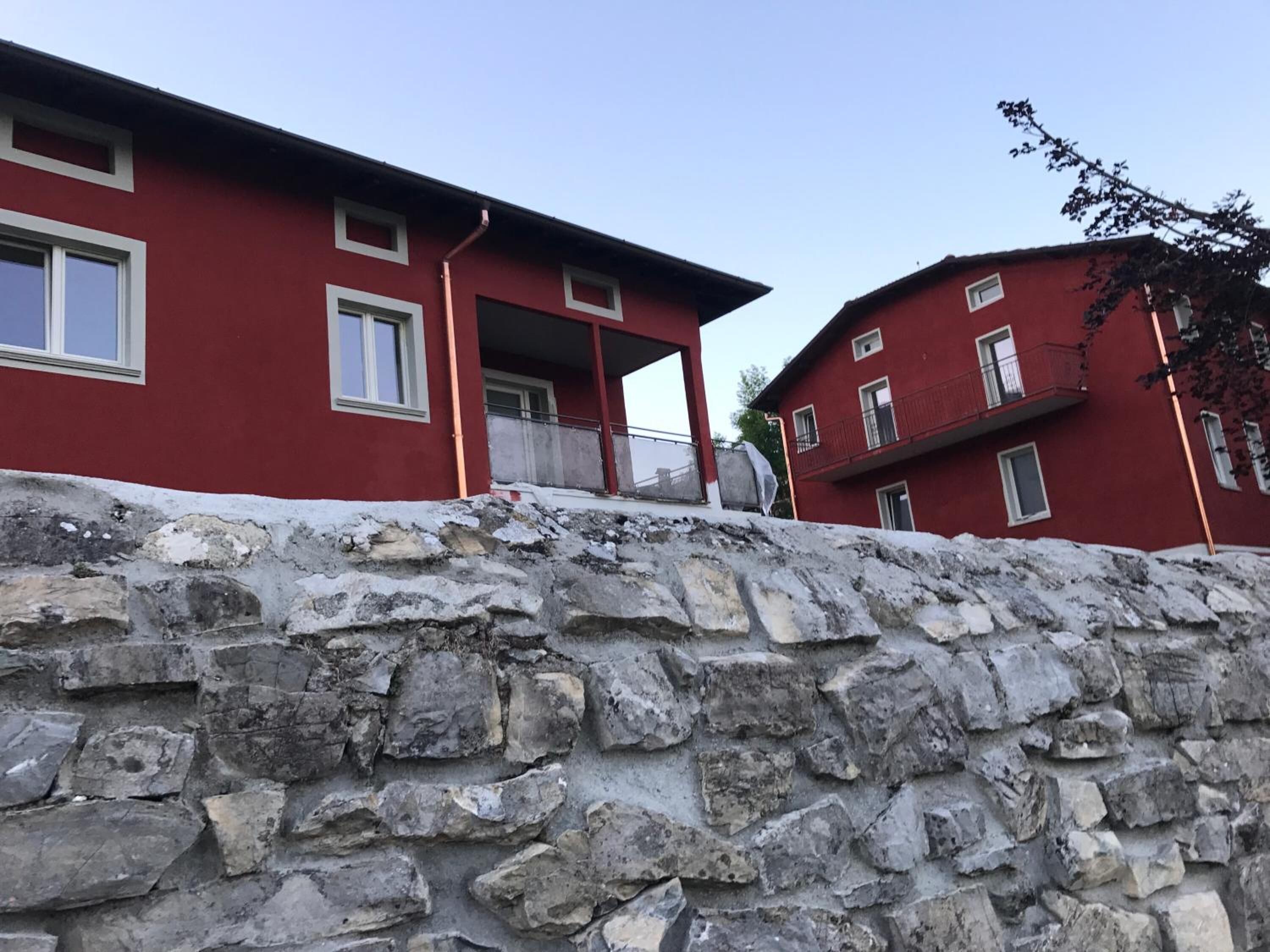 Un edificio rojo con paredes de piedra, múltiples ventanas y balcones.