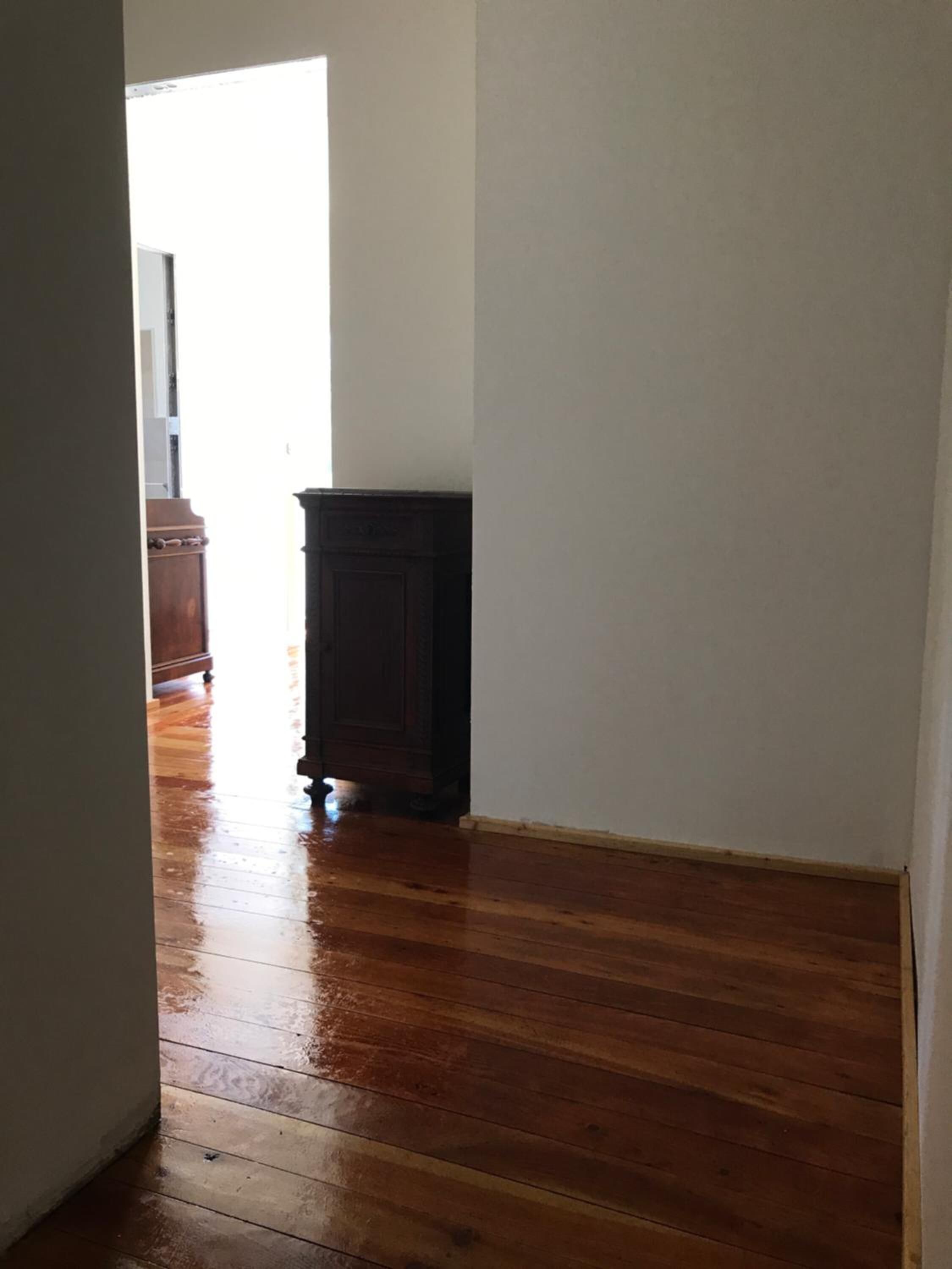 Un couloir doté d’un plancher en bois et d’une armoire en bois foncé.