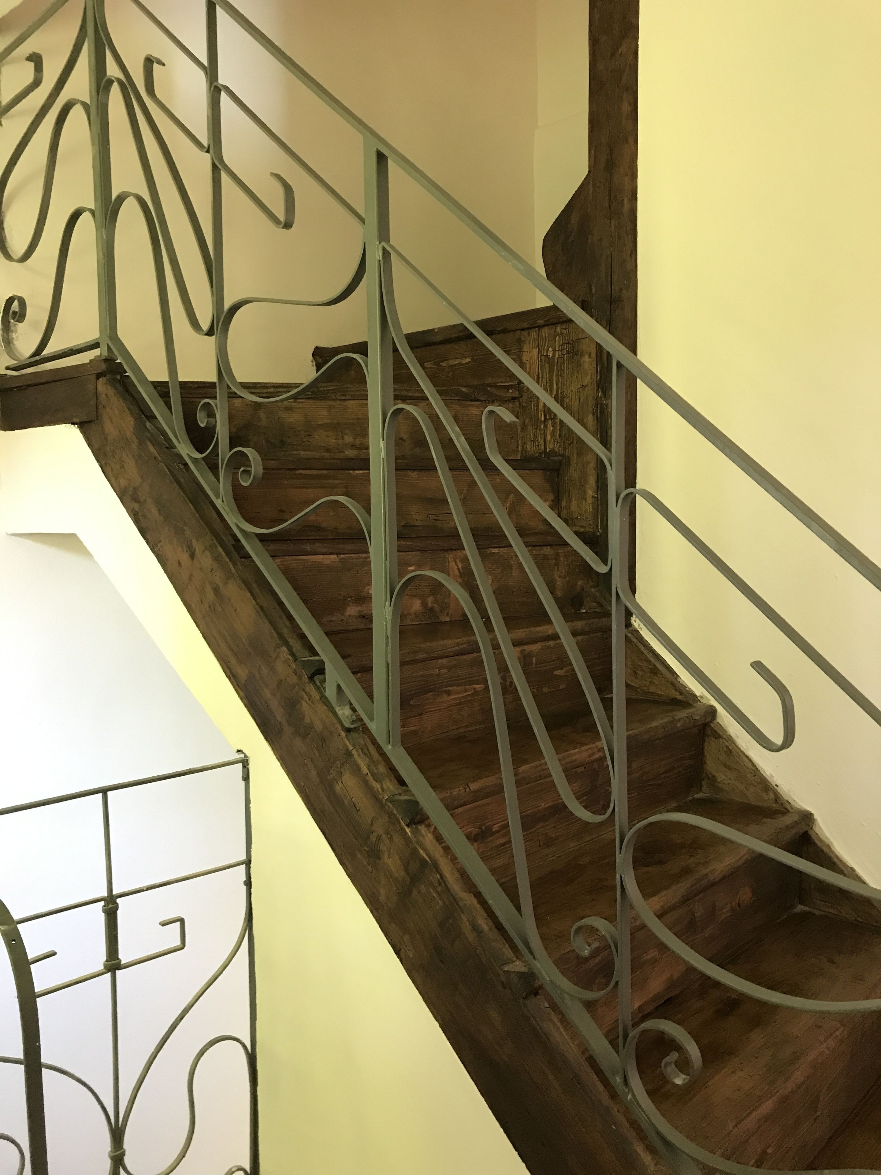 Eine hölzerne Treppe mit aufwendiger Metallreling.