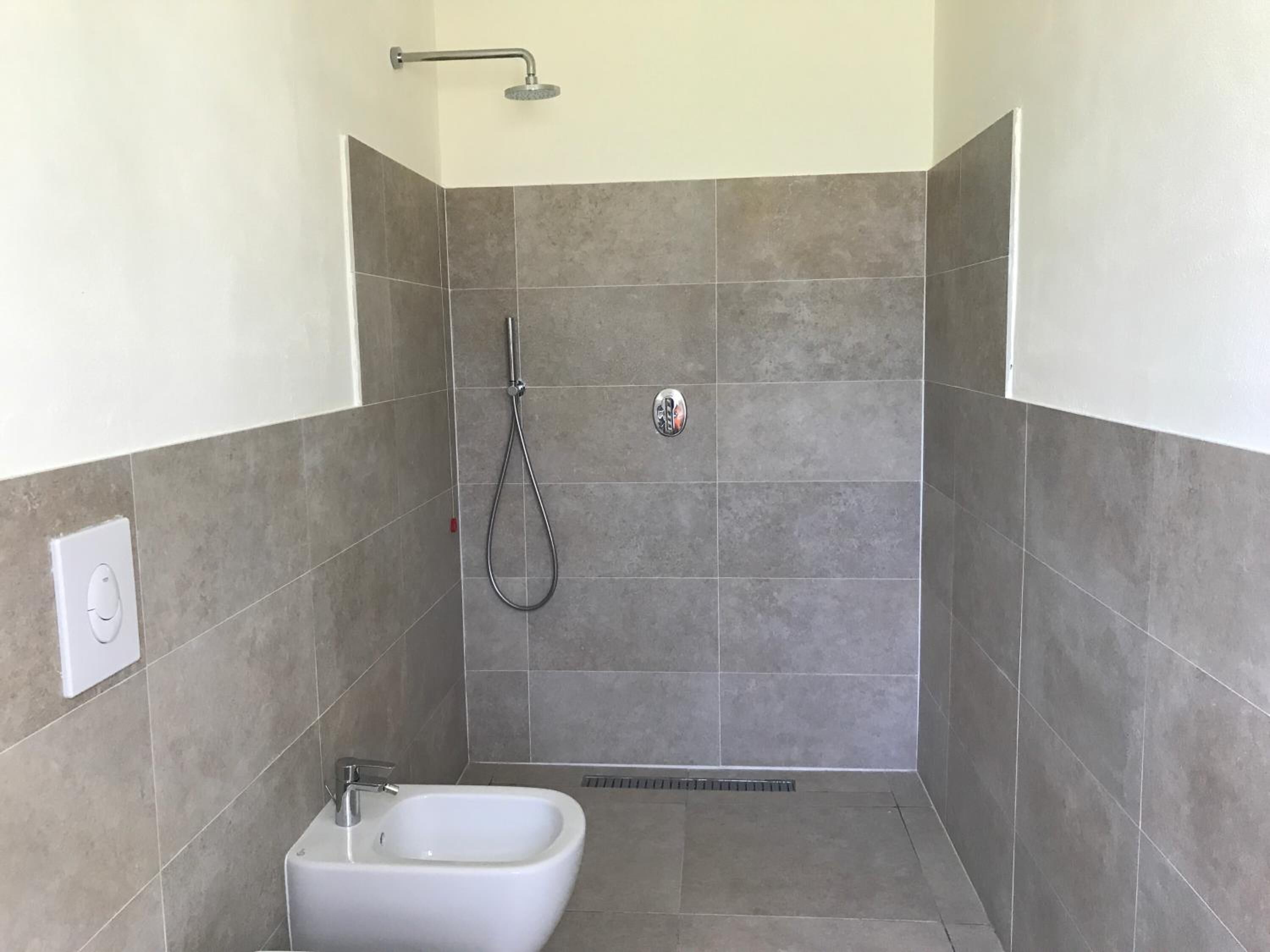 Un baño pequeño y moderno con ducha, bidé e inodoro.