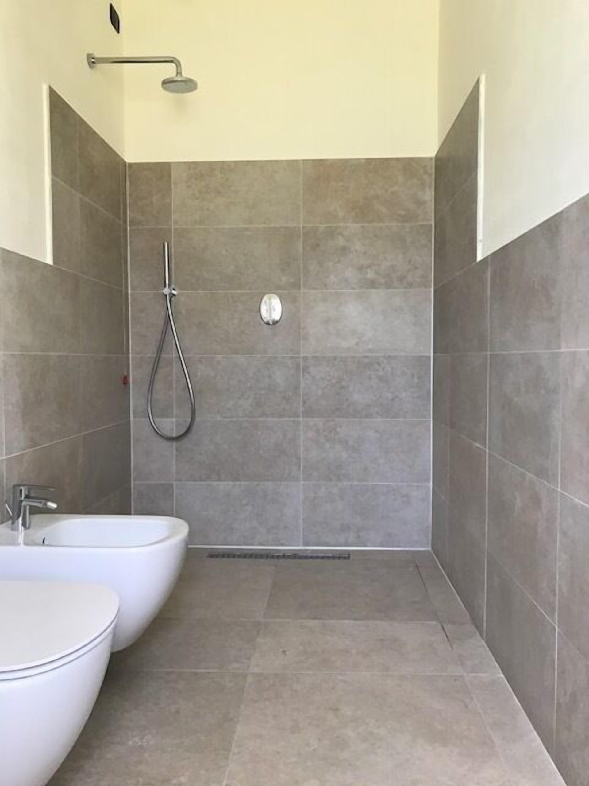 Une salle de bain moderne équipée d’une douche, de deux lavabos et de toilettes.
