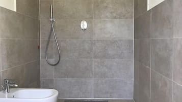 Une salle de bain moderne équipée d’une douche, de deux lavabos et de toilettes.