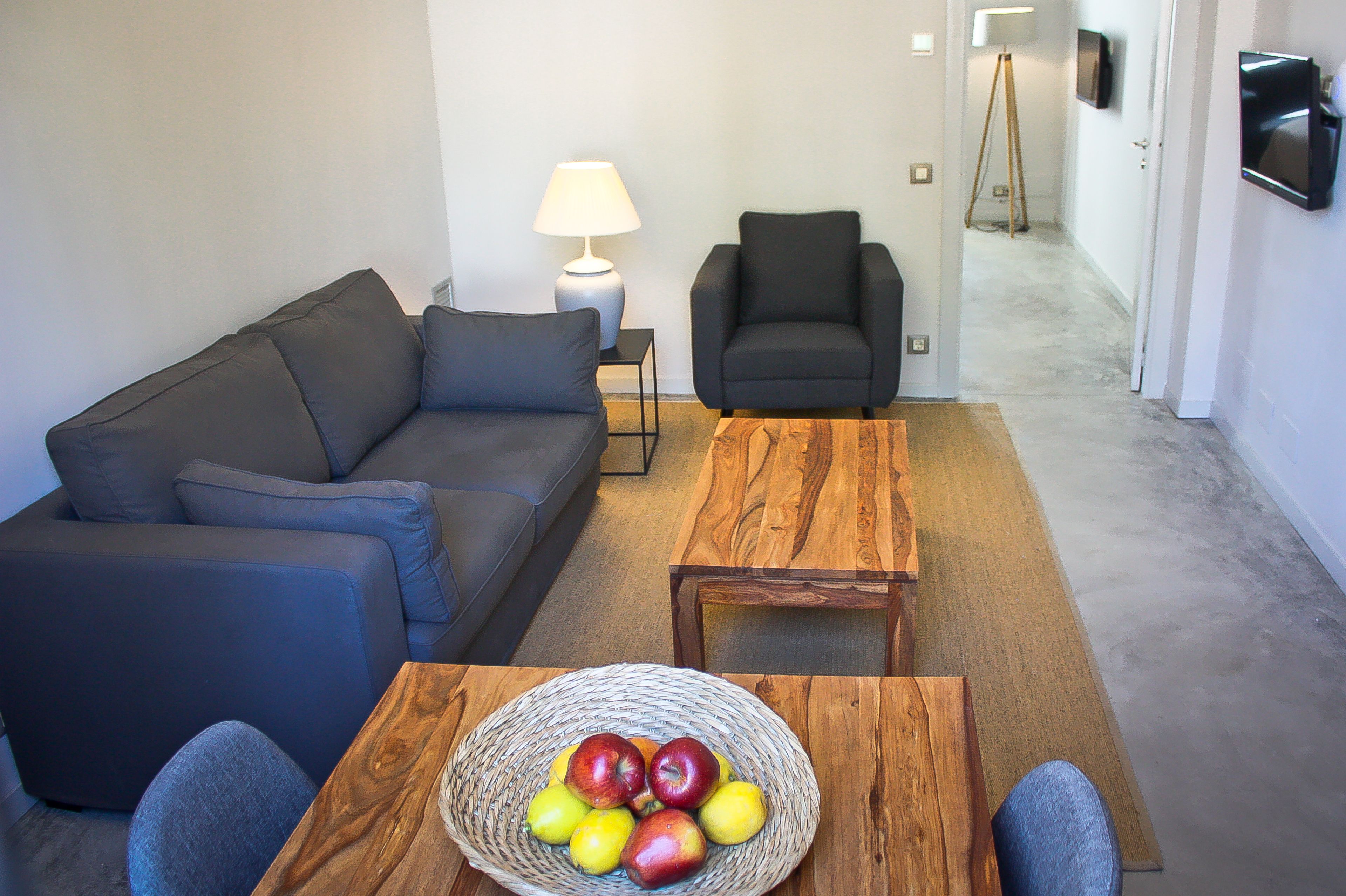 A living room with a sofa, two armchairs, a coffee table, a lamp, and a TV.