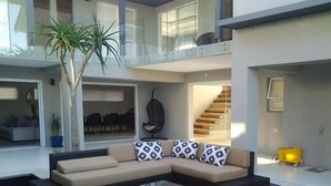 A modern living area with a sectional sofa, a coffee table, and a potted plant. - Grand Blue D (Cape Town)