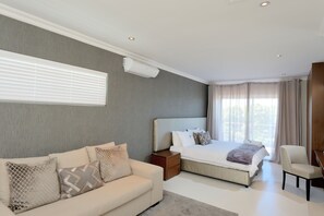 A modern bedroom with a large bed, a sofa, a nightstand, and a chair. - Grand Blue D (Cape Town)