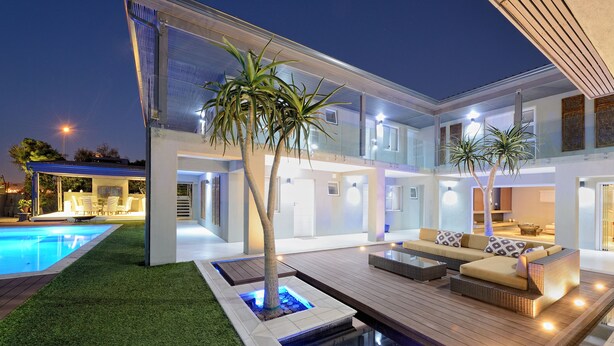 A modern house with a swimming pool, outdoor seating, and a well-lit patio area. - Grand Blue D (Cape Town)