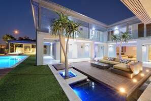 A modern house with a swimming pool, outdoor seating, and a well-lit patio area. - Grand Blue D (Cape Town)
