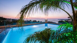 A swimming pool with a view of the sunset and distant buildings. - Esplanade Apartments (Chania)