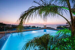 Una piscina con vista al atardecer y edificios lejanos.