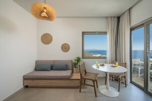 Una sala de estar moderna con sofá, mesa de comedor, sillas, lámpara colgante y un amplio ventanal con vistas.