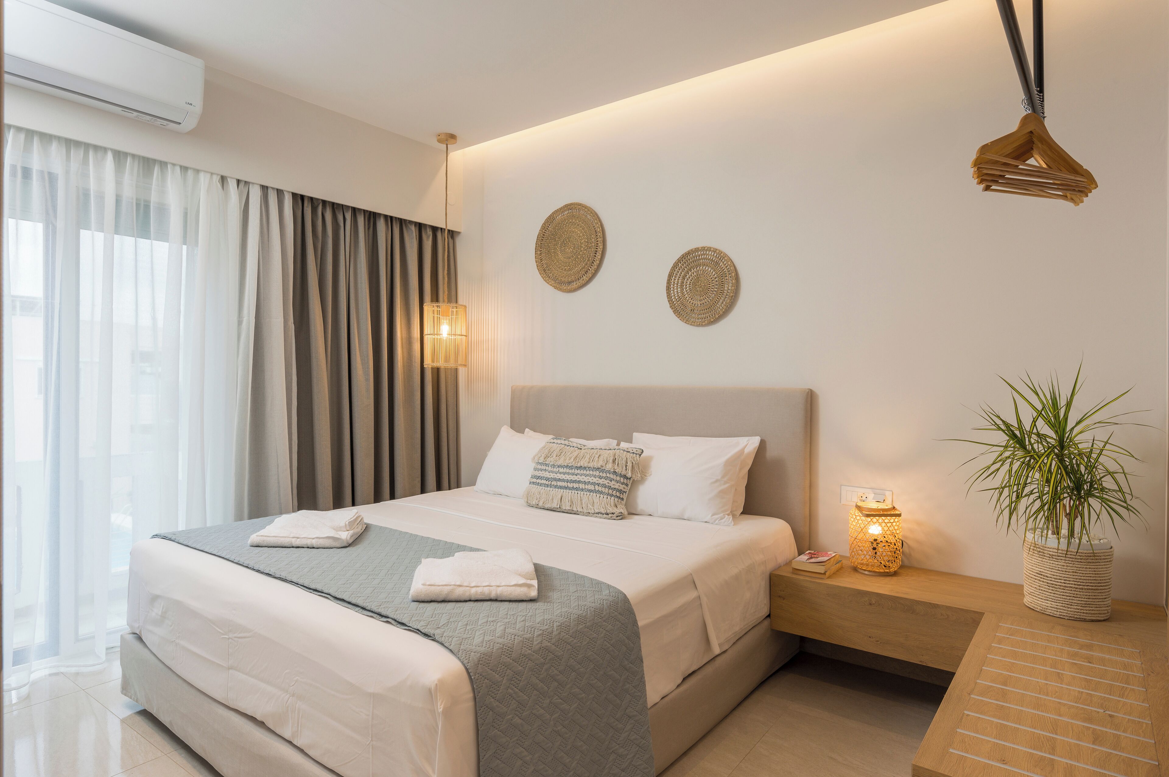 A modern bedroom with a large bed, bedside tables, a potted plant, and decorative wall art.