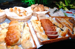 A variety of bread and pastries displayed in baskets and trays. - Hotel Manta (Pelotas)