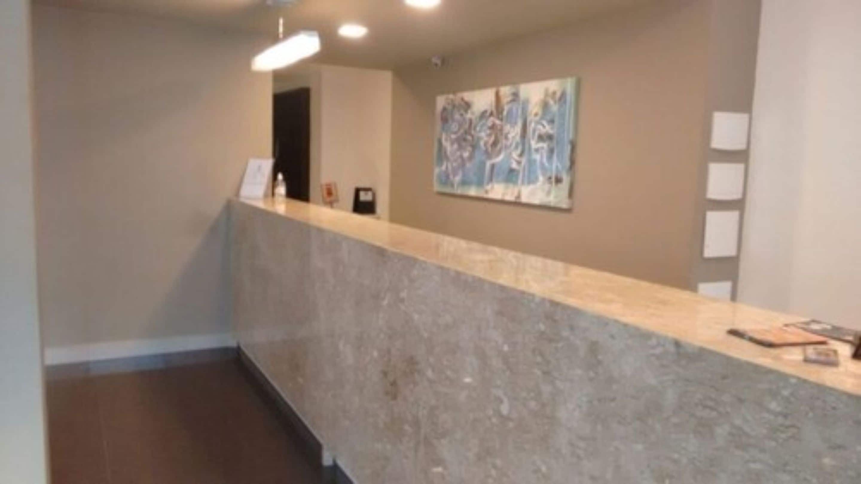 A reception area with a marble counter, a framed abstract painting on the wall, and a door in the background.