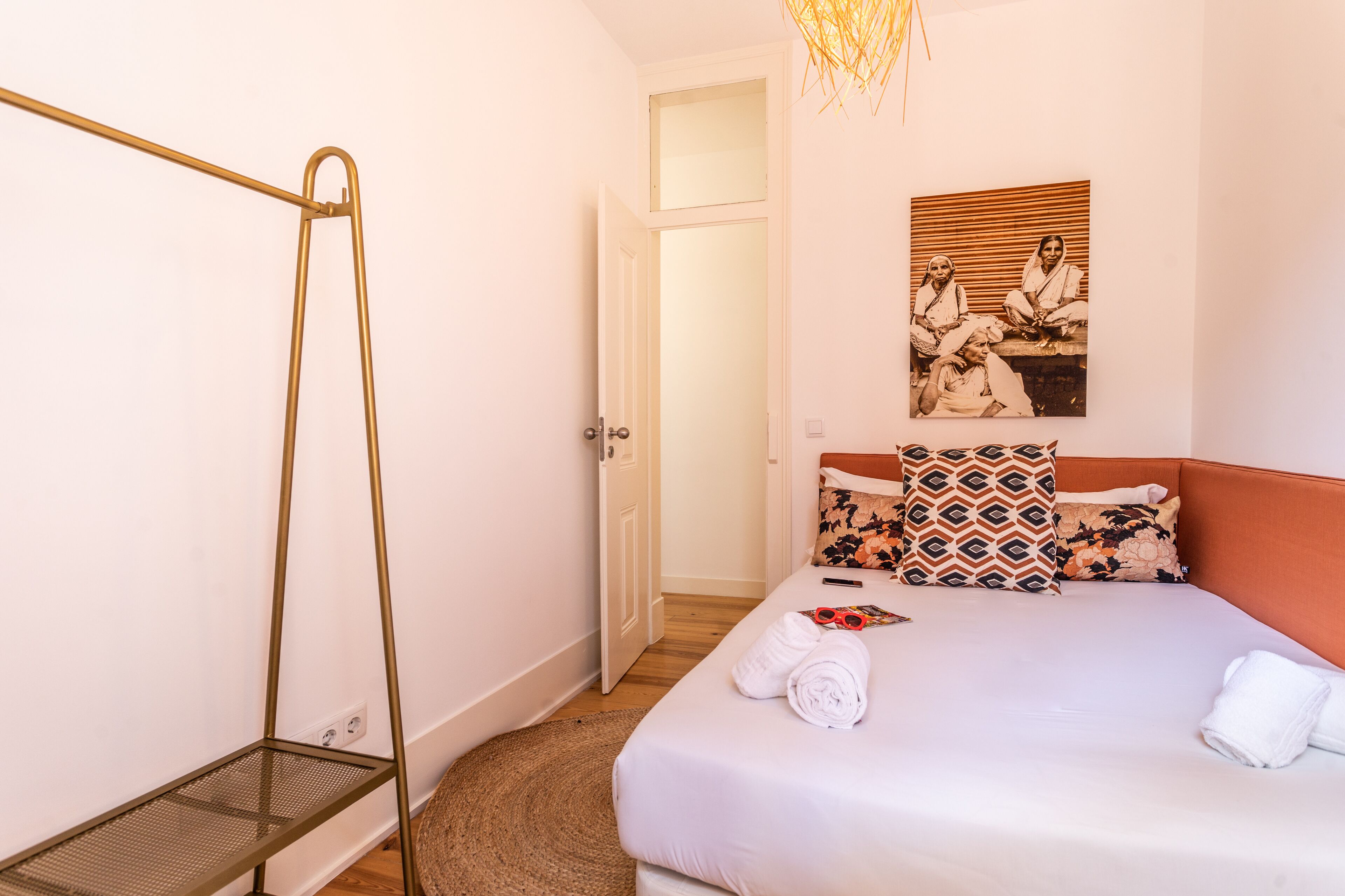 Une chambre avec un lit, un étagère en métal, une porte et un tableau accroché au mur.