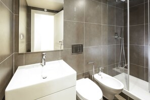 A modern bathroom with a large mirror, a sink, a toilet, and a glass-enclosed shower area.
