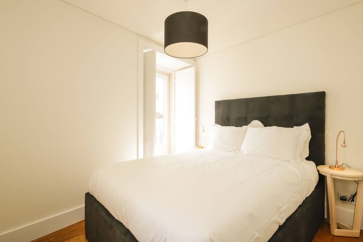 Ein Schlafzimmer mit einem großen Bett, einem Nachttisch und einer Hängeleuchte.