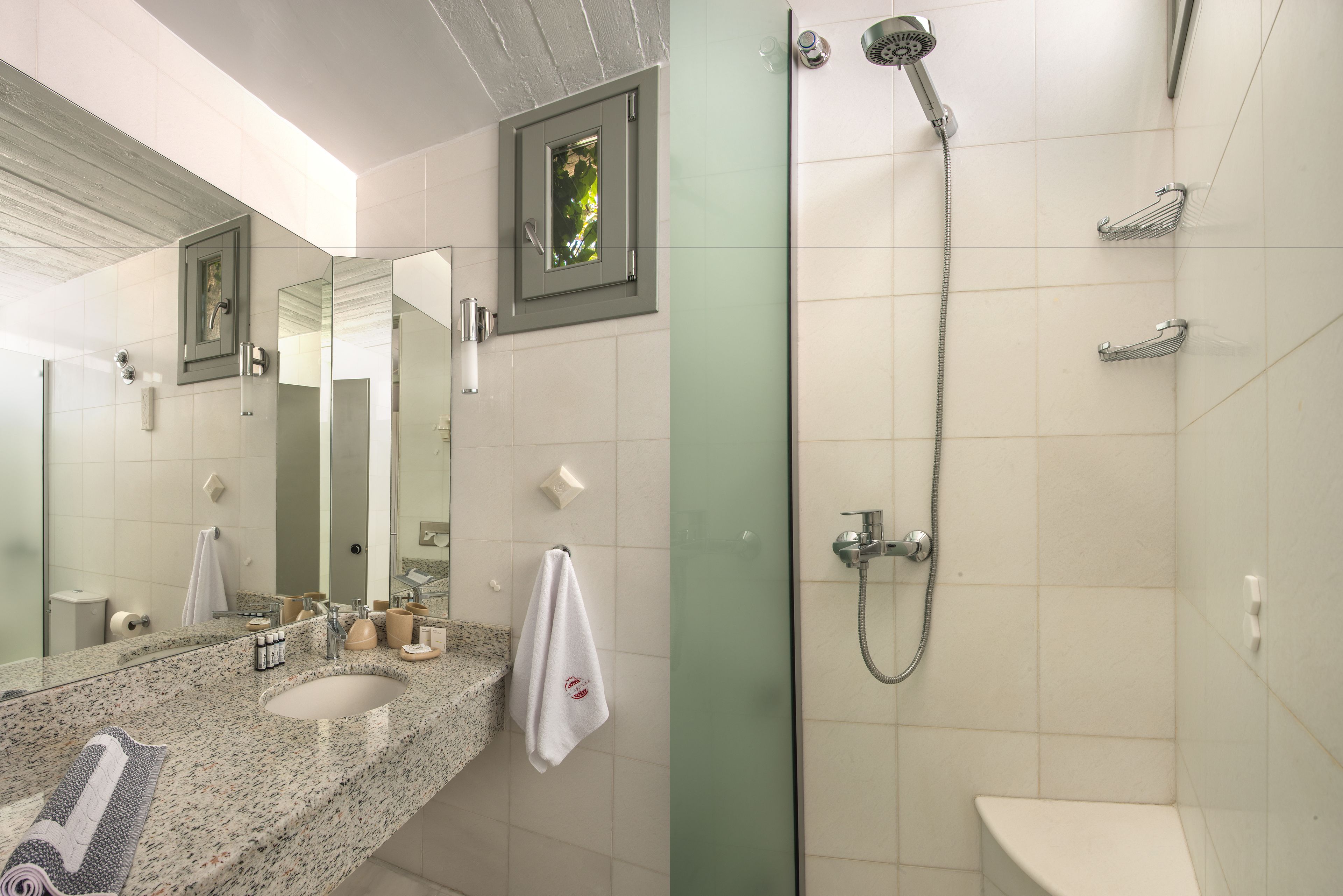 A modern bathroom with a granite sink, a large mirror, a shower with a handheld showerhead, and a toilet.