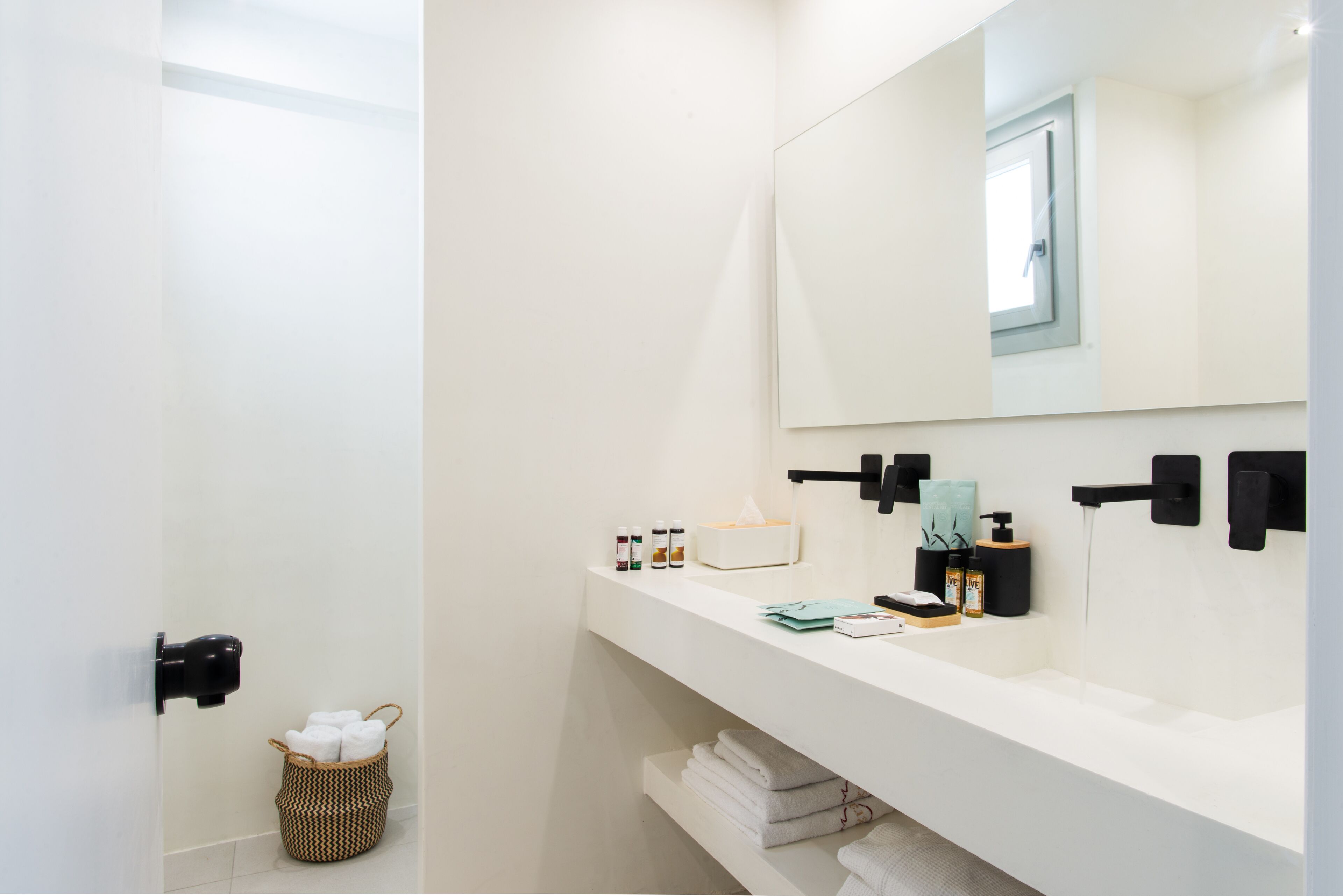 A modern bathroom with a white vanity, a large mirror, and a towel rack.