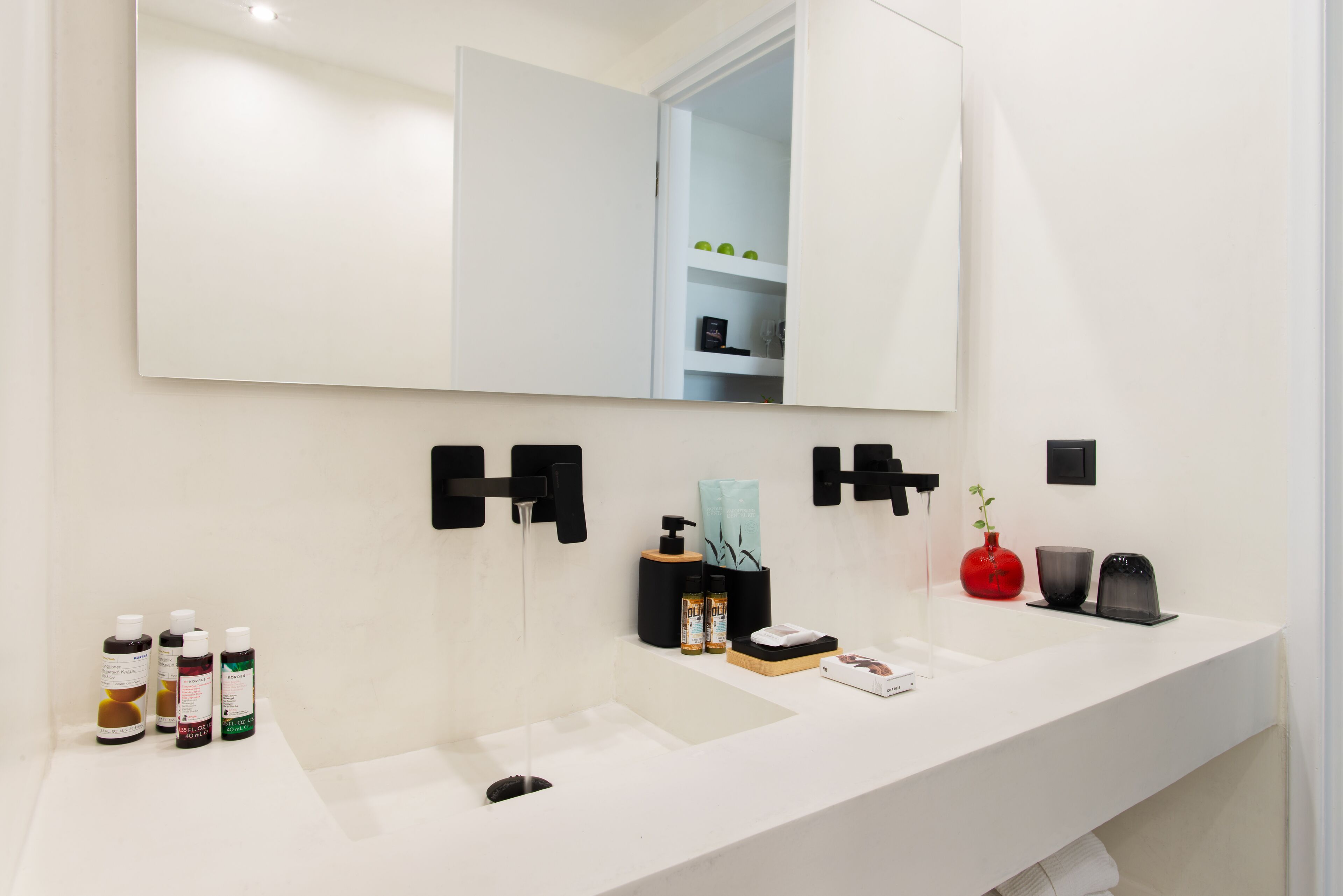 Un baño moderno con un espejo grande, dos lavamanos y distintos artículos de tocador.