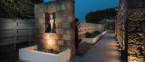 A stone structure with a statue, surrounded by white planters and a pathway.