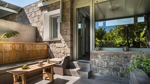 A stone exterior with a wooden bench and a potted plant. - Melagrana (Milos)