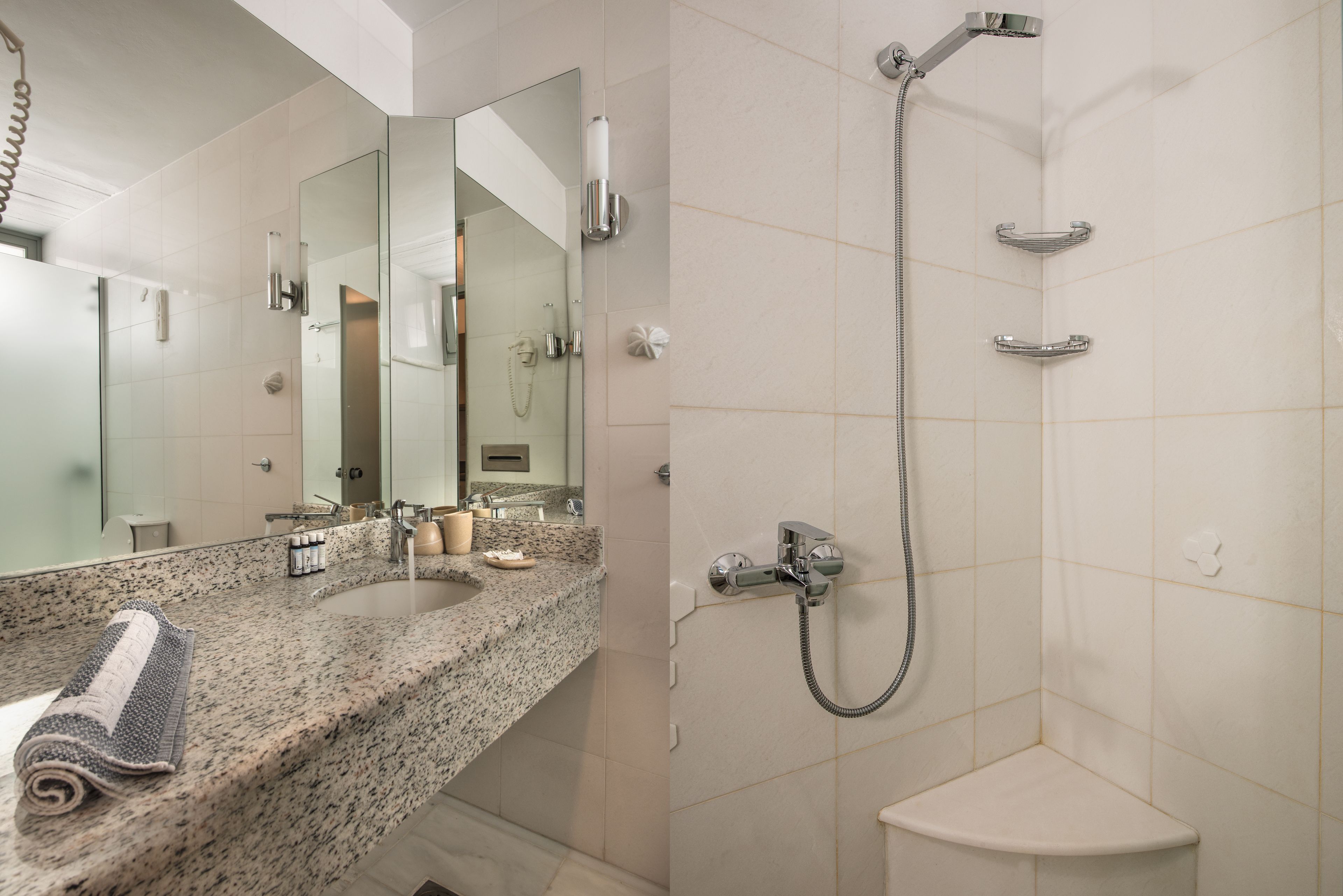 A modern bathroom with a granite countertop, a large mirror, a shower with a handheld showerhead, and a toilet.