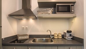 A modern kitchen with a stainless steel sink, a microwave, a coffee maker, and a basket on the countertop. - Melagrana (Milos)