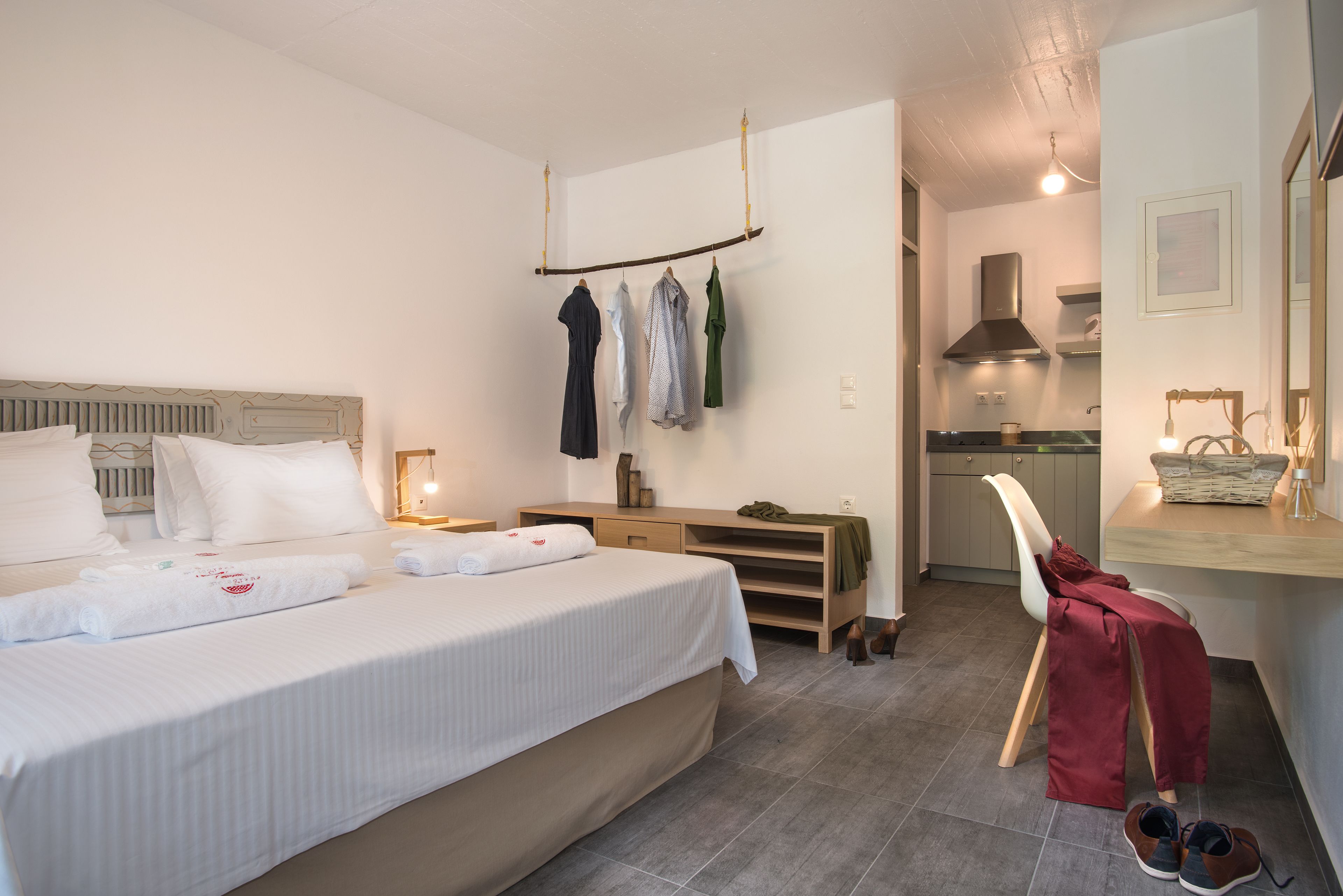 Una habitación de hotel con cama, escritorio, silla y kitchenette.