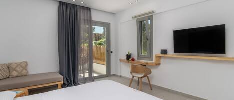 A modern bedroom with a large bed, a desk, a TV, and a sliding glass door to a balcony.