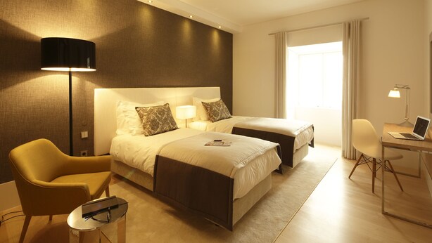 Une chambre d’hôtel avec deux lits, un bureau, une chaise et une lampe.