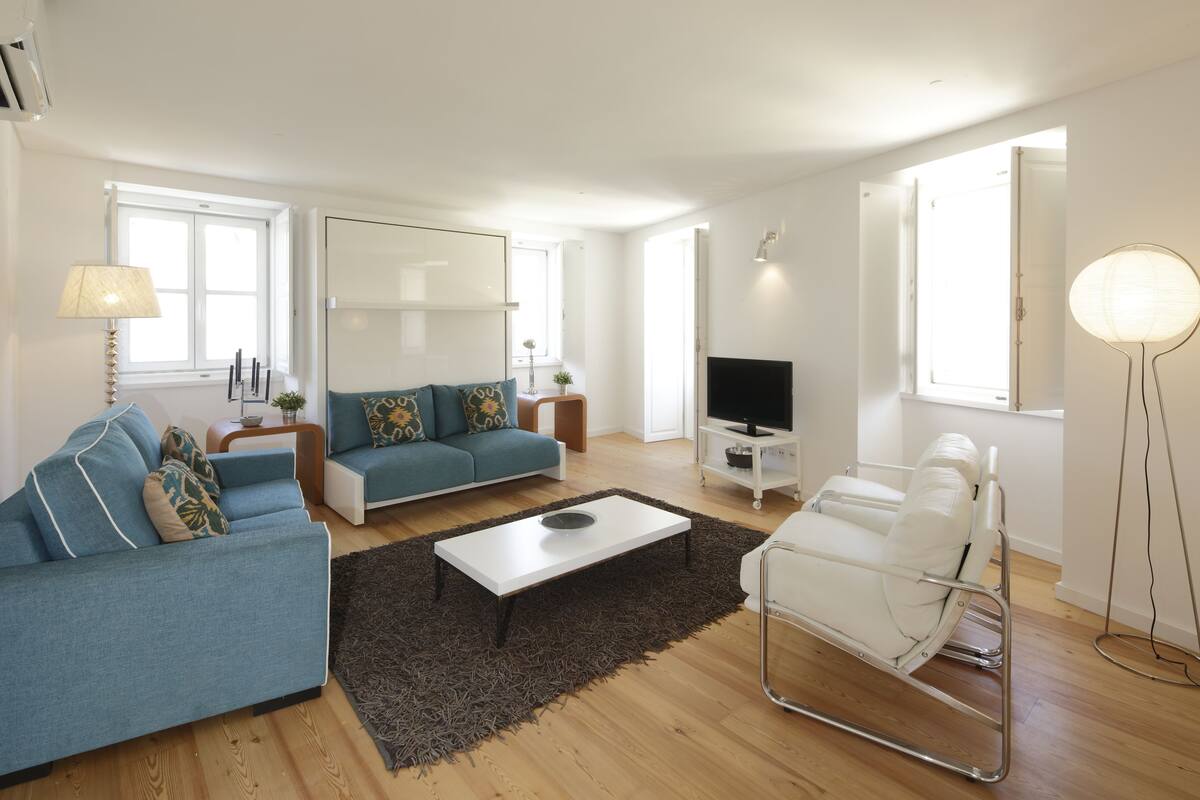 A modern living room with a blue sofa, a white coffee table, and a white chair.