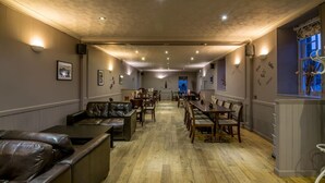 A spacious dining area with wooden flooring, leather seating, and wall-mounted light fixtures. - The Boyne Hotel (Banff)