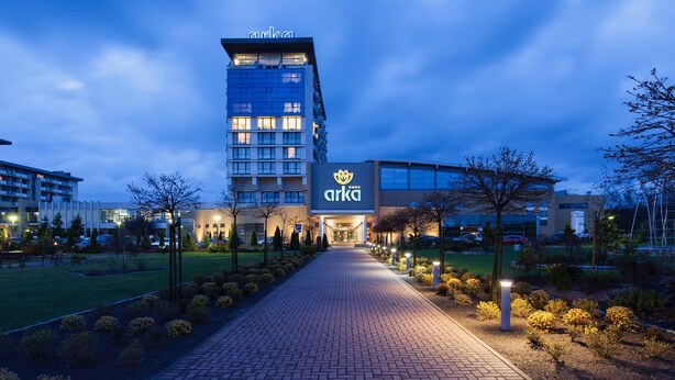 A hotel entrance with a paved pathway leading to the building, surrounded by landscaped areas and trees.