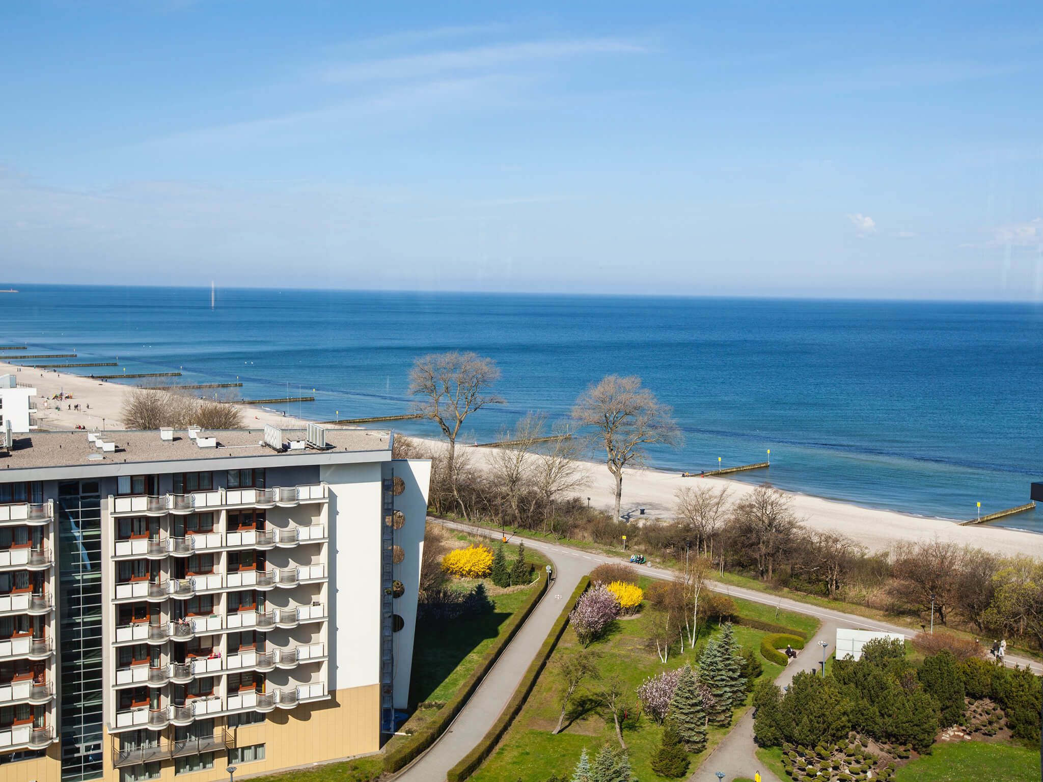 Un hotel alt amb nombroses galeries que donen a una platja i al mar.