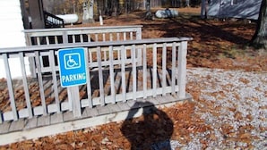 Señal de estacionamiento para discapacitados en una valla de madera en zona boscosa.