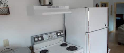 Cocina compacta con estufa, horno y refrigerador.