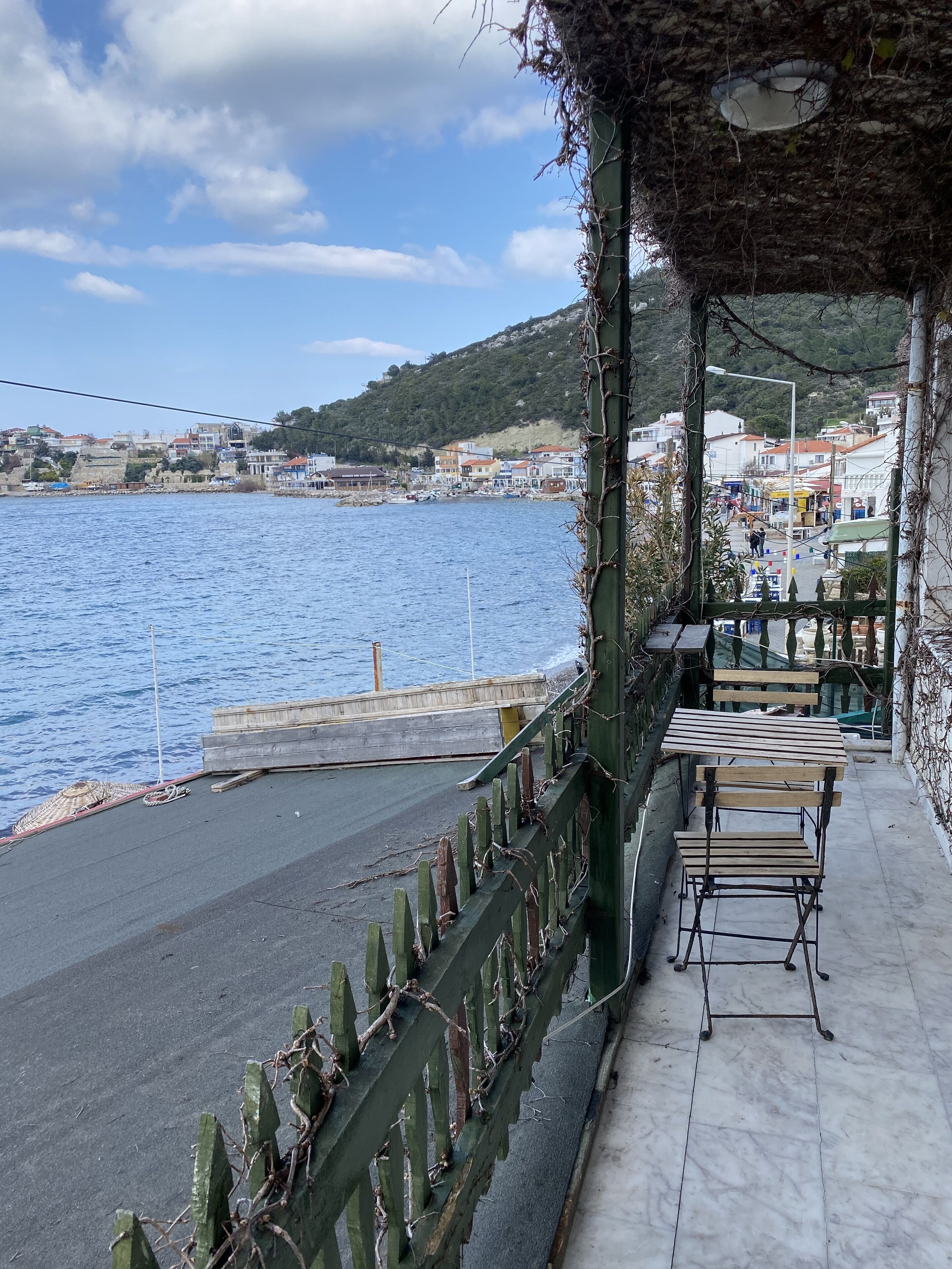 A seaside terrace with a view of the sea and a town in the background.
