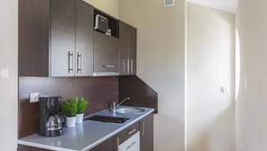 A compact kitchen with dark cabinets, a stainless steel sink, and a coffee maker.
