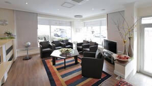 Una sala de estar moderna con un televisor grande, asientos cómodos y un jarrón decorativo.