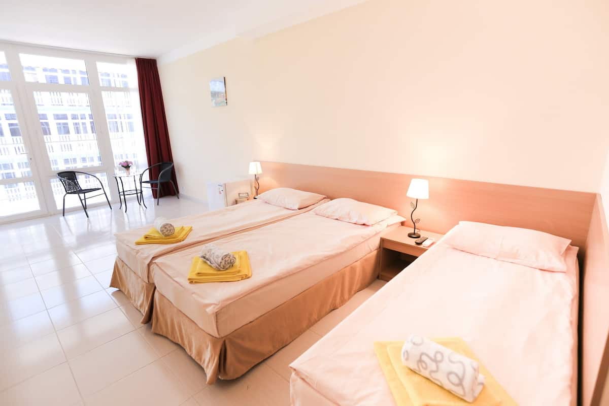 A hotel room with two beds, a desk, a chair, and a large window.