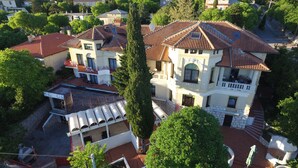A multi-story building with a tiled roof, a central courtyard with a fountain, and a surrounding garden. - Hotel Ruža (Novi Vinodolski)