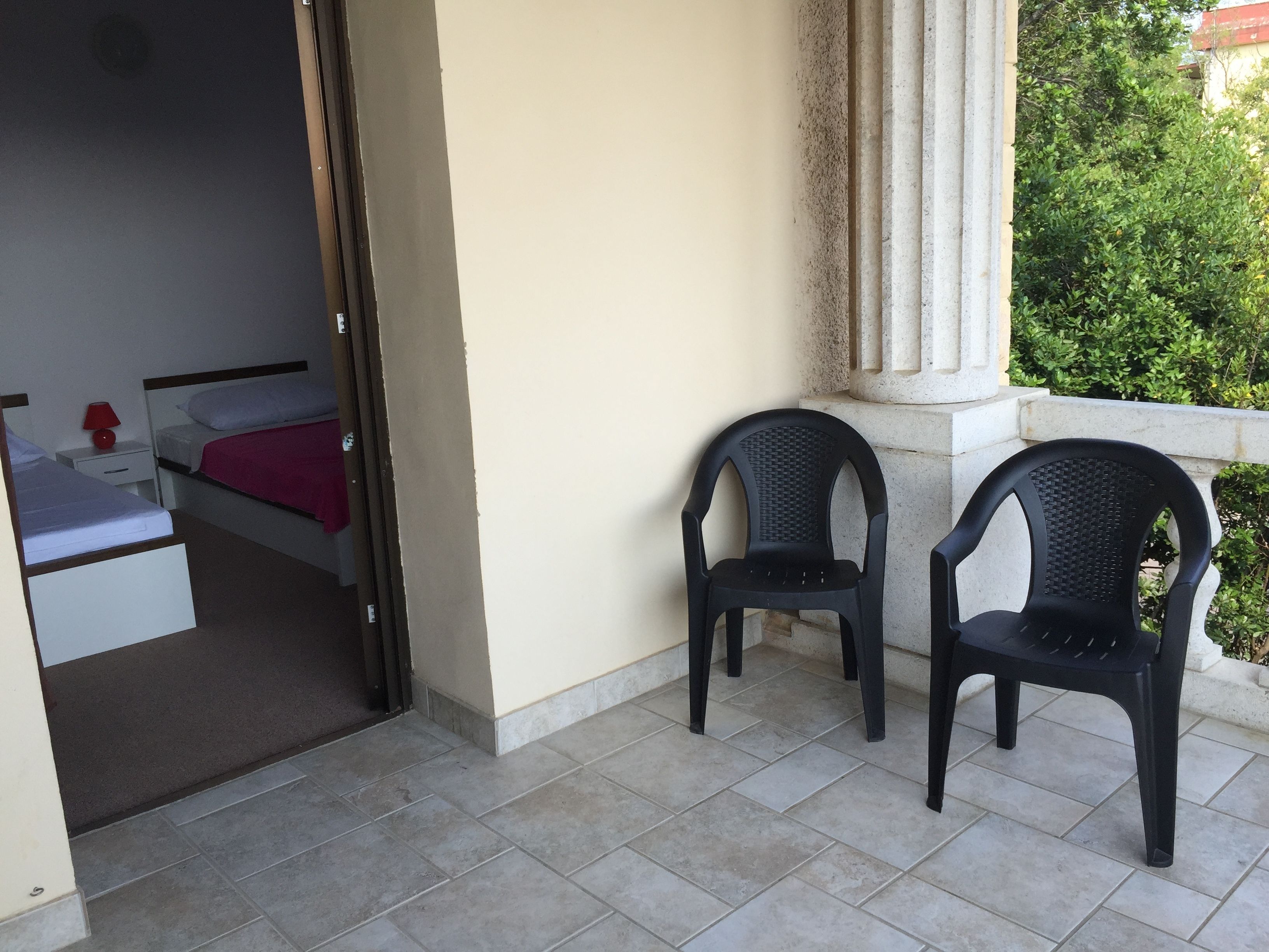 A room with a bed, a nightstand, and two chairs.
