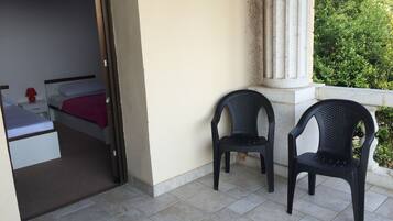 A room with a bed, a nightstand, and two chairs.