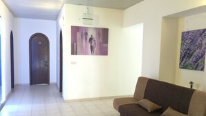 A spacious living area with a brown sofa, a hallway leading to a door, and two wall-mounted paintings. - Hotel Ruža (Novi Vinodolski)