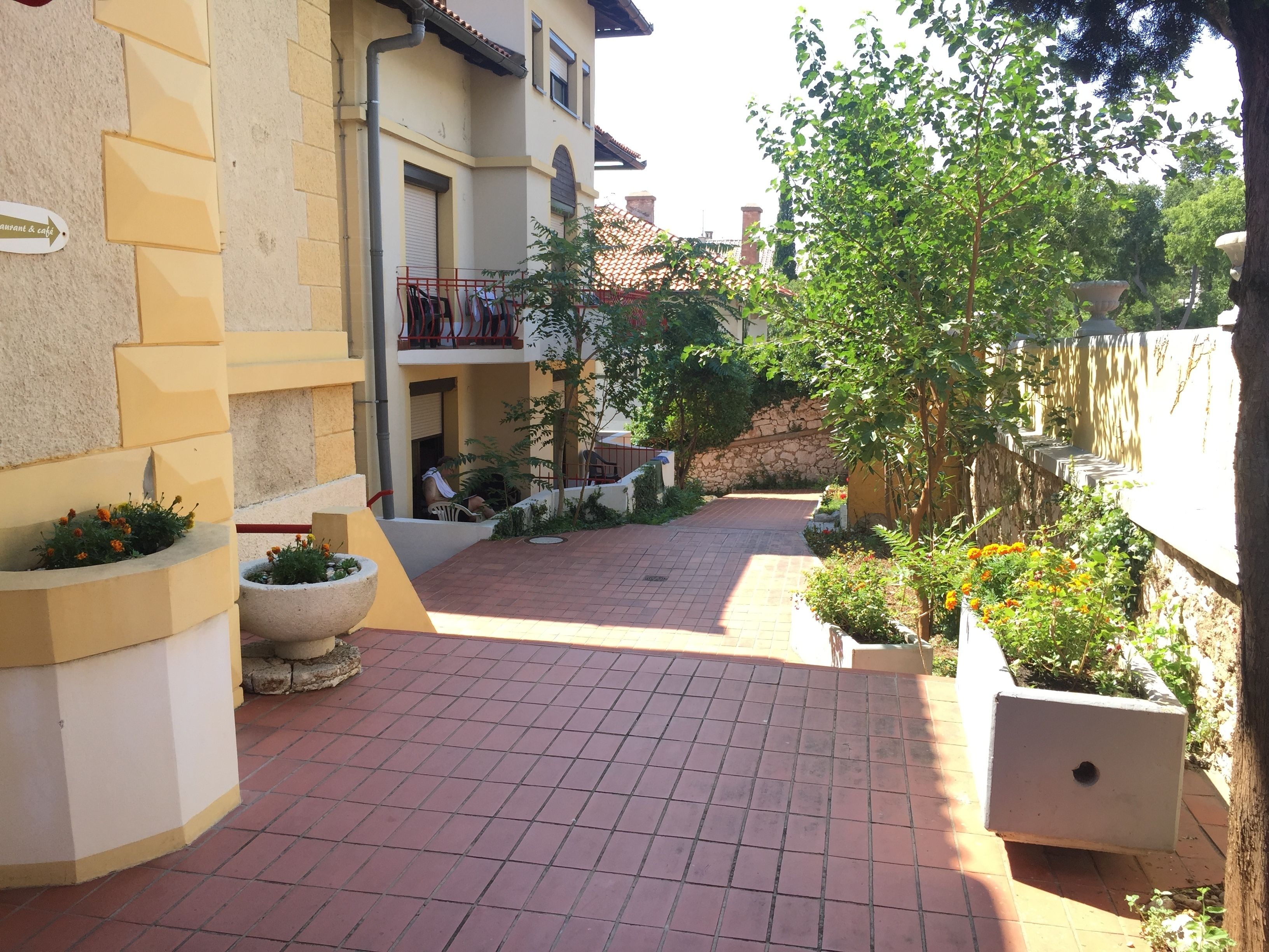 Un patio con suelo de baldosas, plantas en macetas y un edificio con balcón.