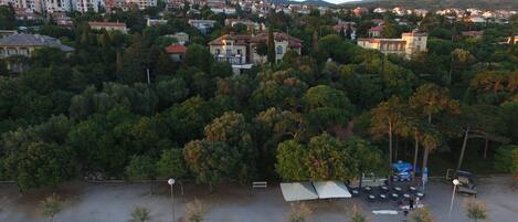 Vista aérea de una zona residencial con abundante vegetación y un área pavimentada con bancos y mesas.