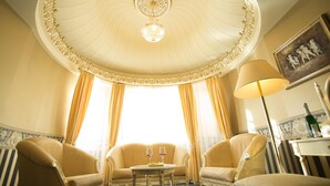 Une chambre luxueuse avec une table ronde, deux fauteuils et un lustre.