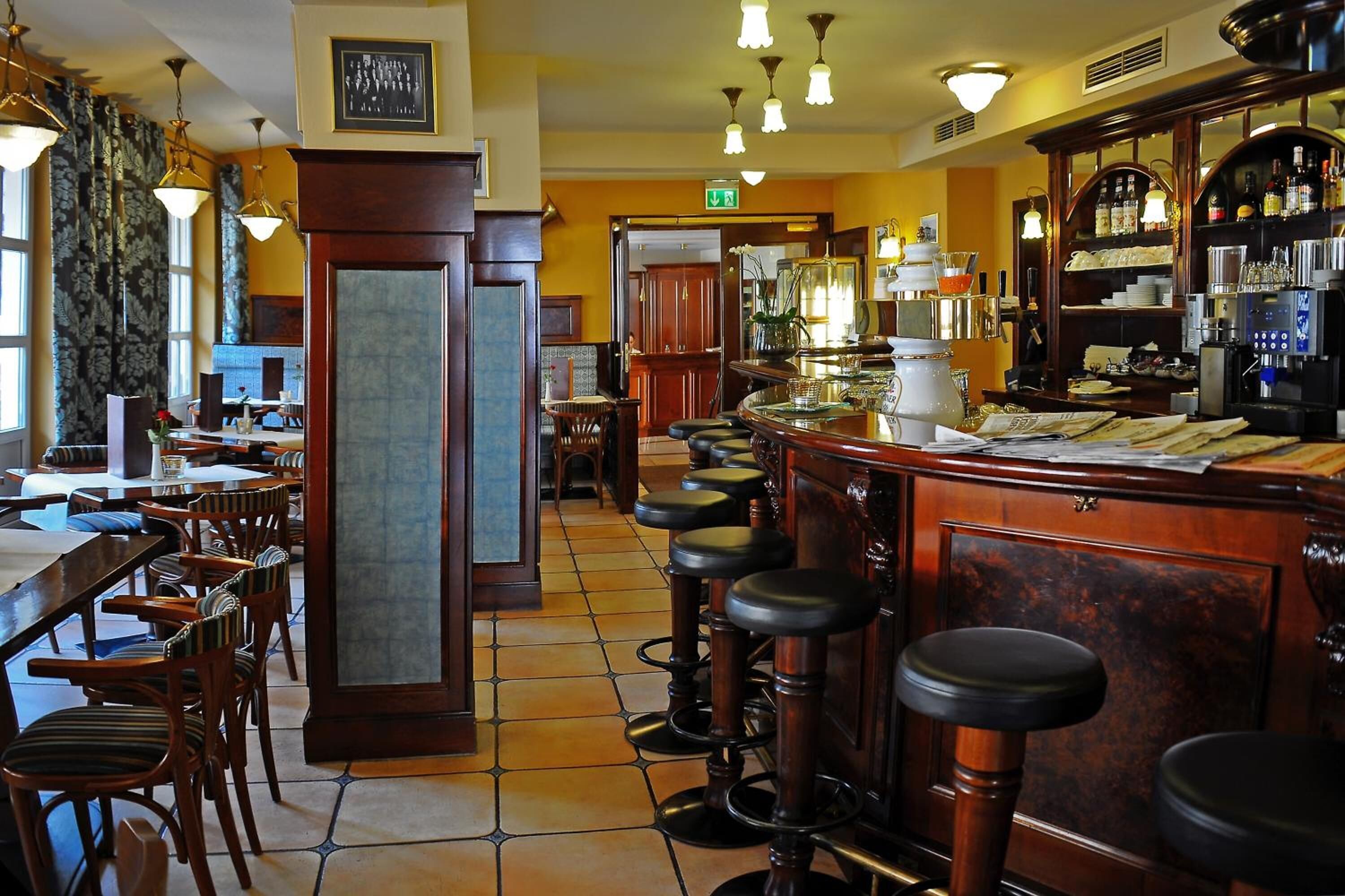 Eine Bar mit hölzernen Barhocker, einer Theke mit Registrierkasse und einer mit Flaschen gefüllten Bar.